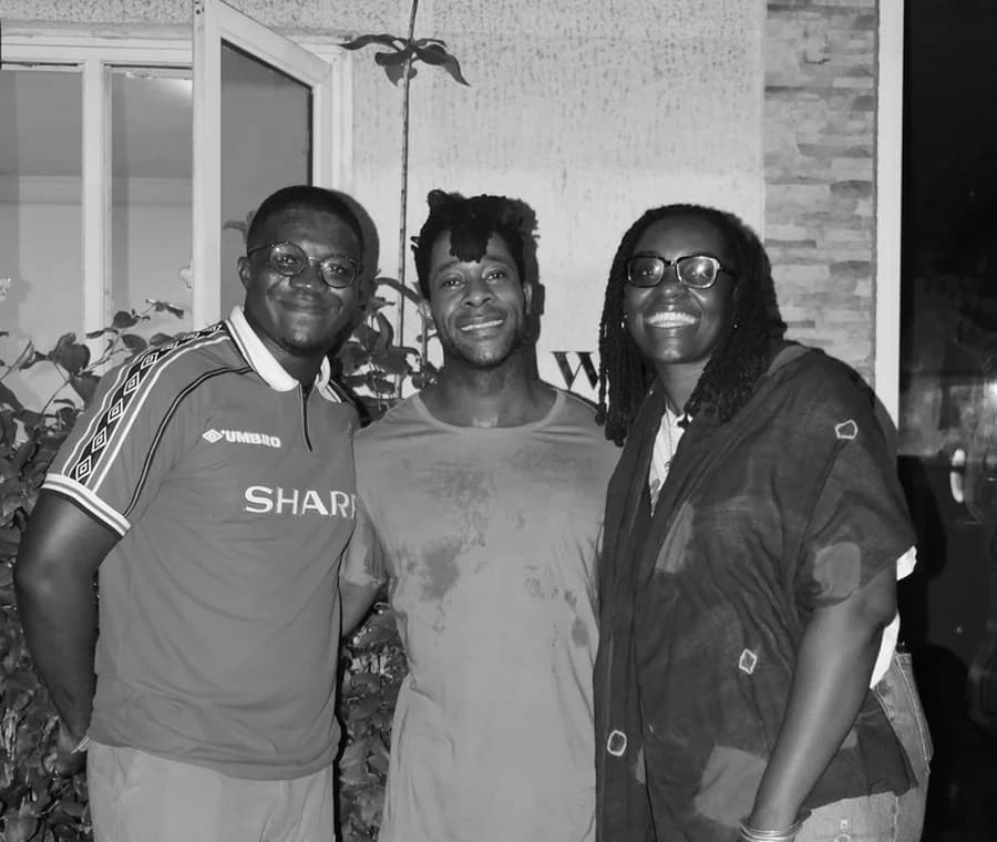 Three filmmakers standing together and smiling at a screening.