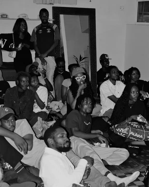 A full room of viewers seated on the floor during a screening.